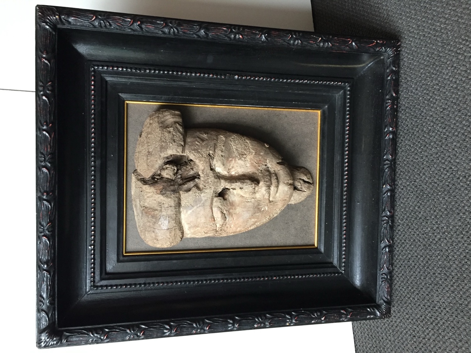 Carved tribal mask mounted in a deep black gilt-lined frame